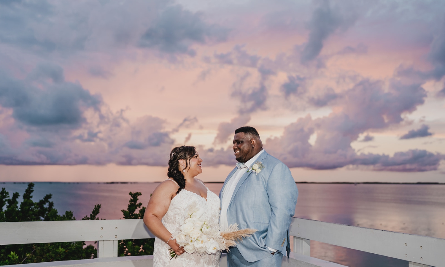 a bride and groom standing outside and looking at each other