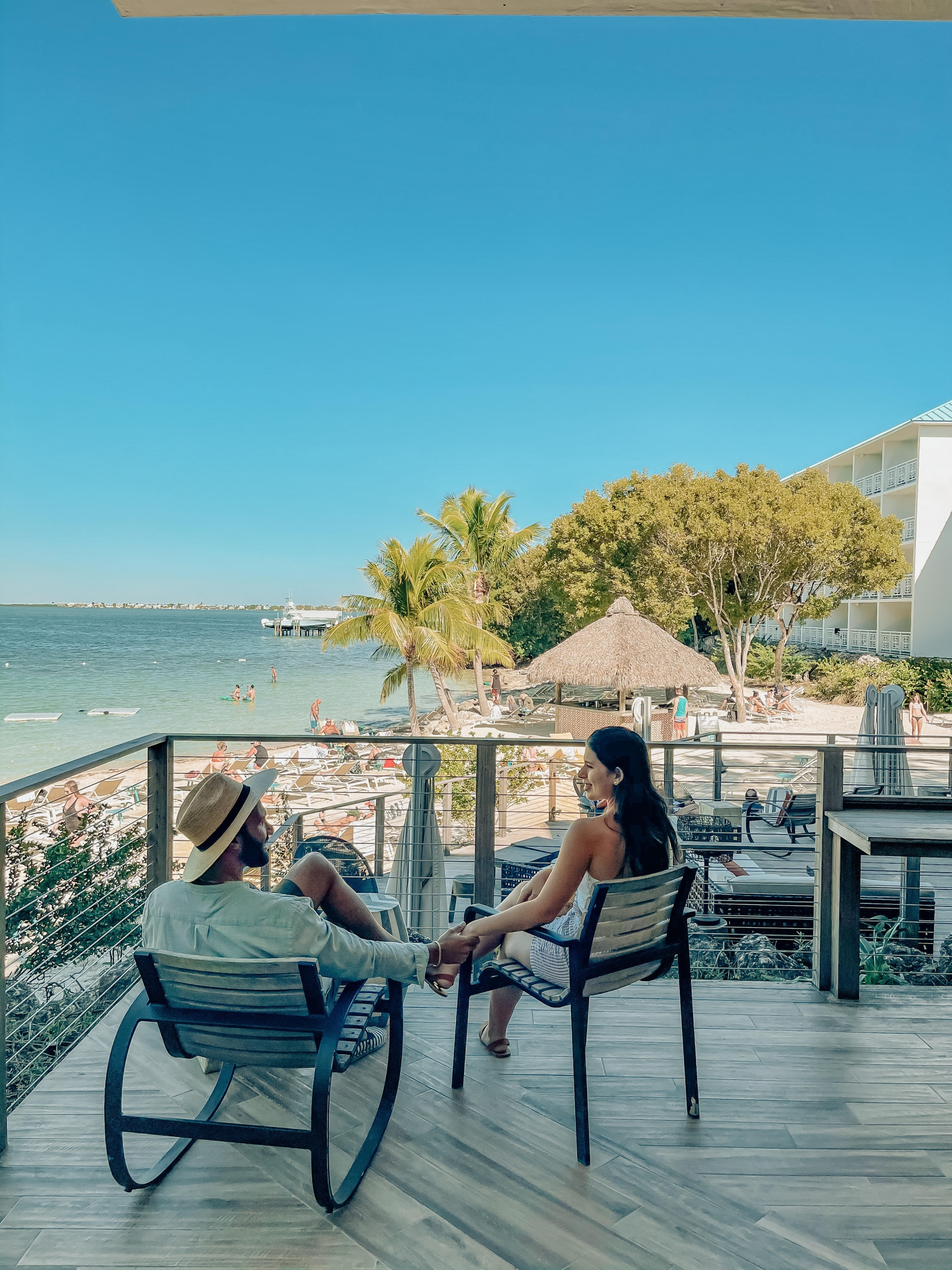 a woman and a man sitting outside on a balcony holding hands