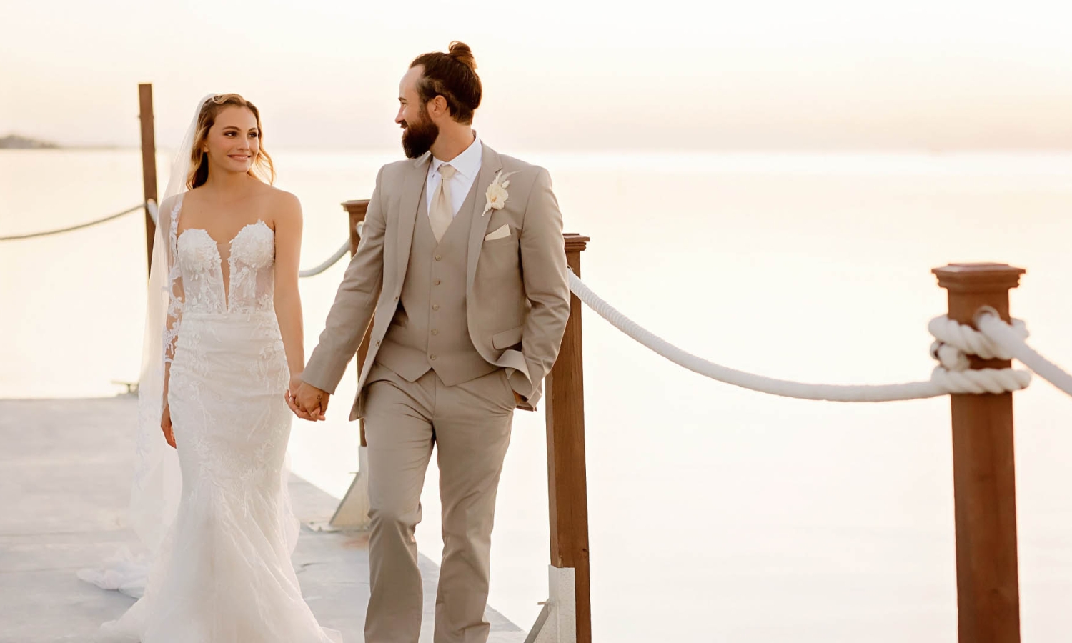 a bride and groom holding hands on a boardwalk