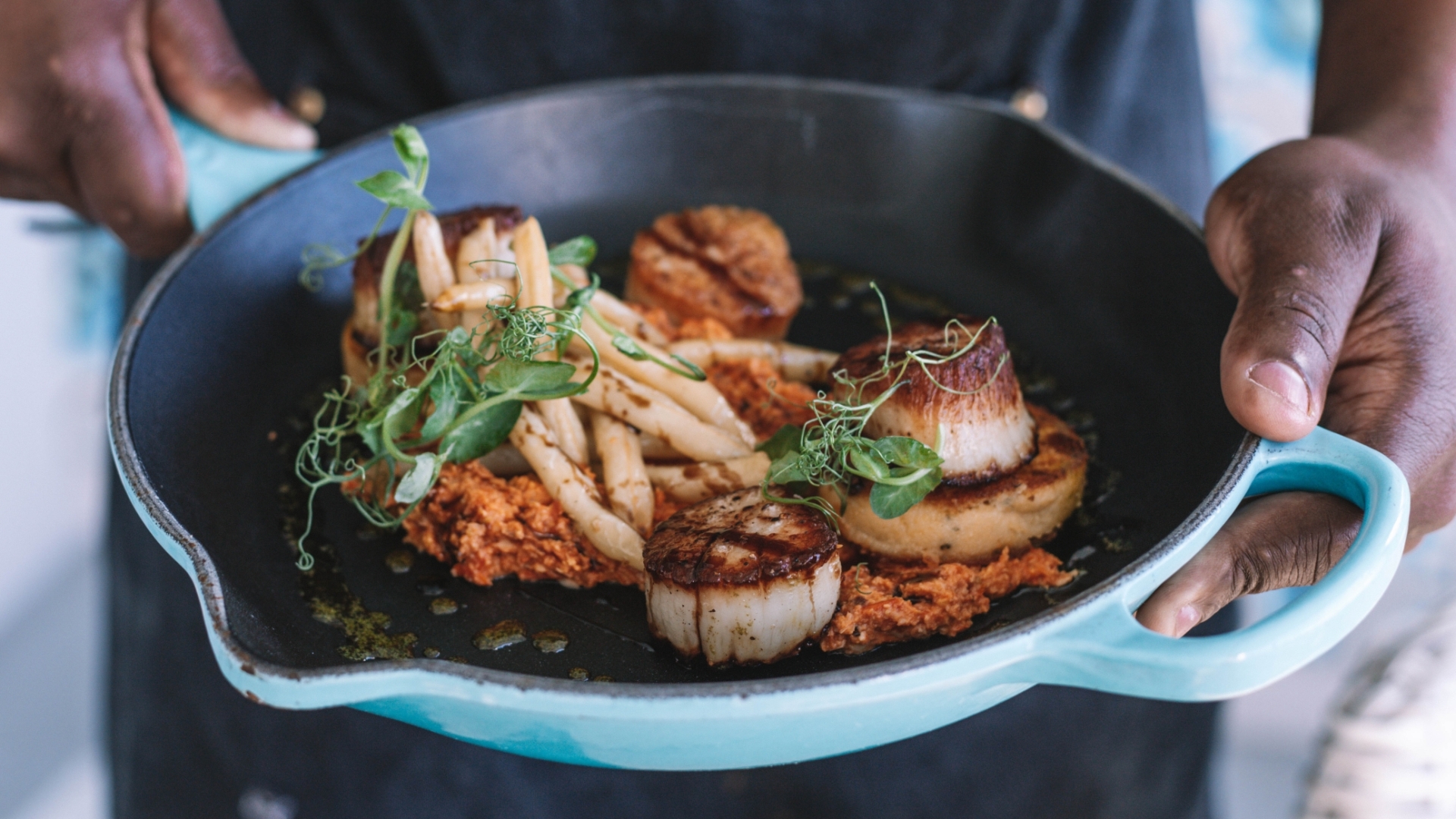 chef holding a dish in a pan