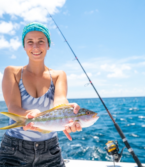 a woman holding a fish on a boat